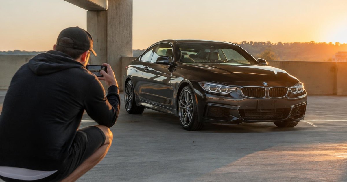 Journal illustration of a person crouching to photograph a dark coupe outdoors at golden hour