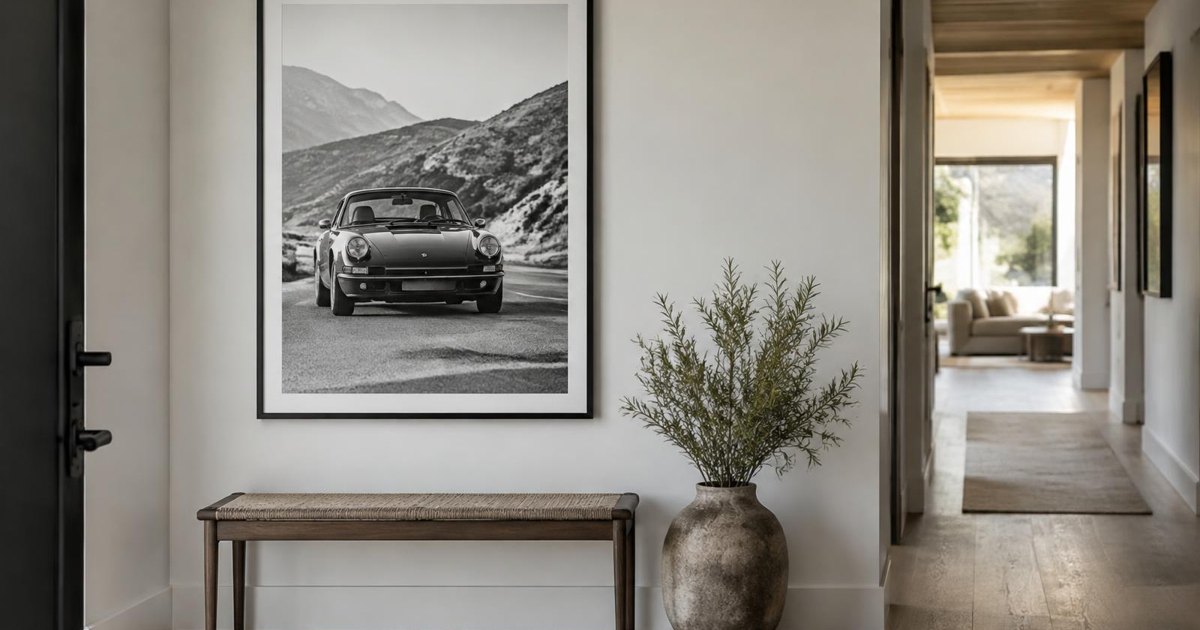 Journal illustration of a framed black-and-white car print on a bright hallway wall above a wooden bench